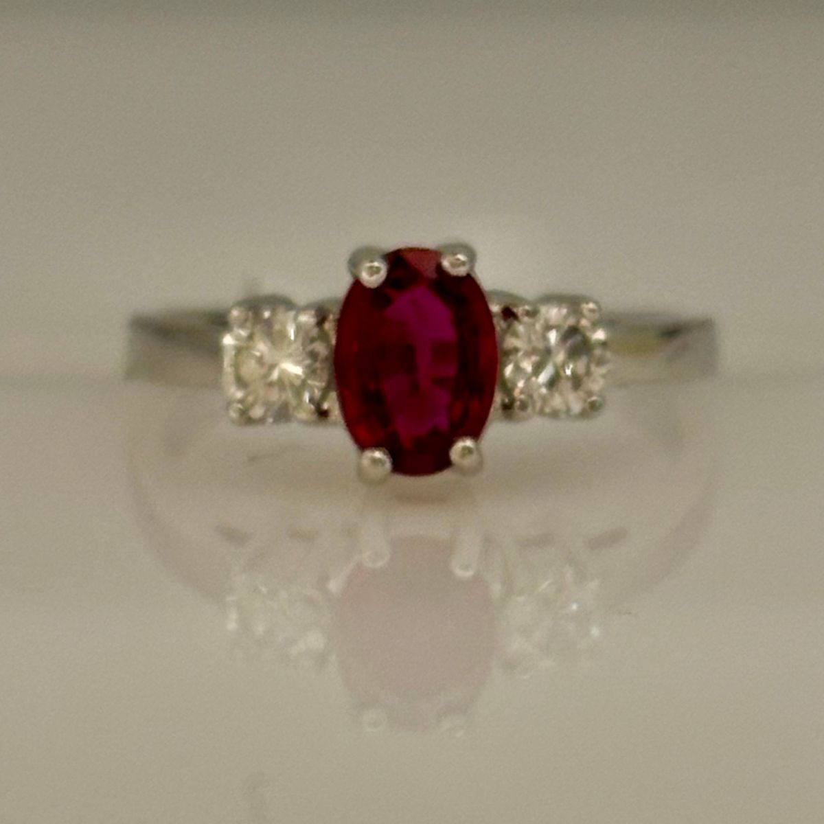 14K WHITE GOLD THREE STONE RING WITH A.56CT OVAL RUBY AND .32CTTW ROUND SI CLARITY & GH COLOR SIDE DIAMONDS
